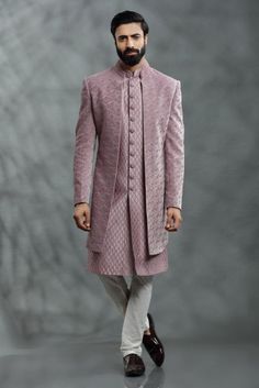 a man in a pink sherwa with white pants and shoes on the runway