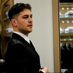 a man in a suit looking at himself in the mirror