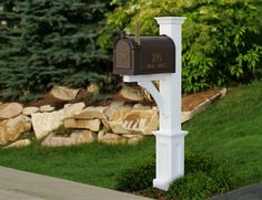 a mailbox in the middle of a lawn with rocks and grass behind it,