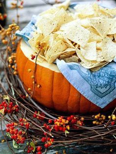 a pumpkin filled with chips sitting on top of a table