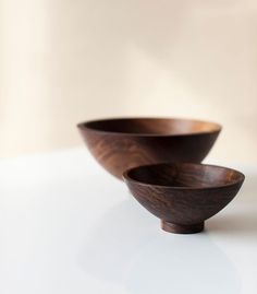 two wooden bowls sitting on top of a white table