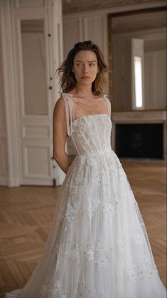 a woman in a white dress standing on a wooden floor