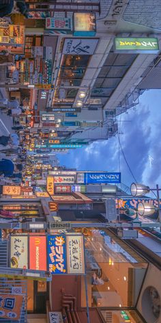 a city street filled with lots of signs and buildings under cloudy skies at night time