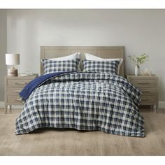 a bed with blue and white plaid comforter on top of it in a bedroom