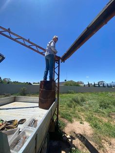 a man standing on top of a metal structure in the middle of a grass field