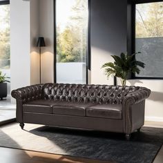 a brown leather couch sitting on top of a rug in a living room next to a window