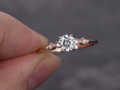 a hand holding a diamond ring in it's left hand, with the center stone on