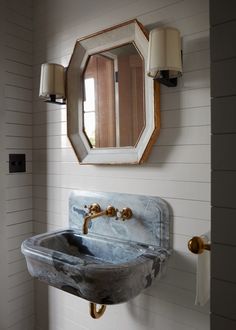 a bathroom sink sitting under a mirror next to a wall mounted faucet and light fixture