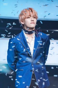 the man is wearing a blue suit and bow tie with confetti around him