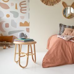 a bed room with a neatly made bed next to a small table and two mirrors on the wall