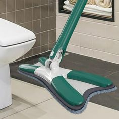 a green and white mop sitting on top of a floor next to a toilet