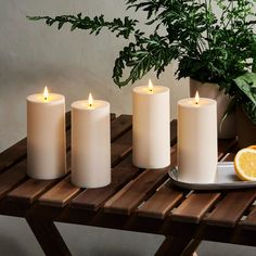 four white candles sitting on top of a wooden table