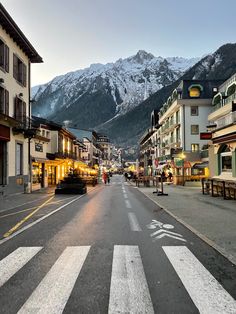 an empty street with buildings and mountains in the backgrouds, at dusk