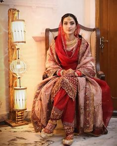 a woman sitting in a chair wearing a red and gold outfit