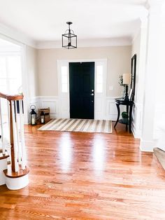 an empty room with hard wood floors and white trim on the walls, along with a black door