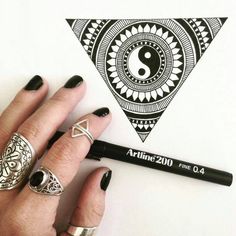 a woman's hand with black nail polish and rings on her fingers next to a pen