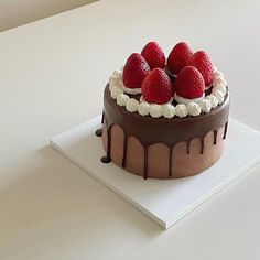 a chocolate cake with strawberries on top and drizzled in icing