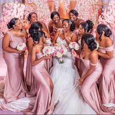 a group of women standing next to each other in front of a flower covered wall