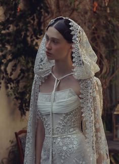 a woman in a white wedding dress with a veil on her head and long sleeves