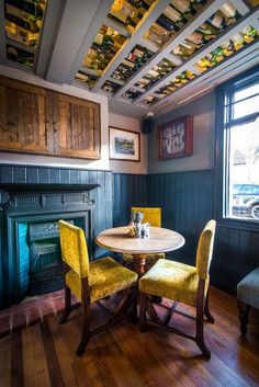 two yellow chairs sitting at a table in front of a fire place