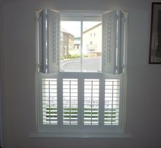 an open window with white shutters in a room