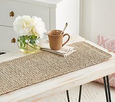 a table with a coffee cup on it and flowers in a vase next to it