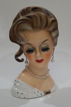 a ceramic figurine of a woman with pearls on her head and red lips