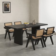 a dining table with four chairs and a bowl of fruit on the table next to it