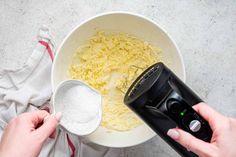 a person mixing food in a bowl with a blender on the side and a measuring cup next to it