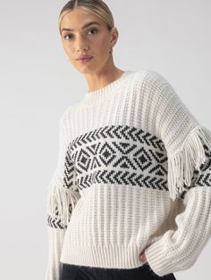 A person poses in the Artisan Fringe Sweater Chalk And Black by Sanctuary Clothing, set against a plain grey background. They have light hair pulled back and are wearing small hoop earrings. Linen Leggings, Rib Sweater, Fringe Sweater, Jacquard Knit, Sweater Sale, Knitted Jumper, Ribbed Sweater, Black Pattern, Black Sweaters