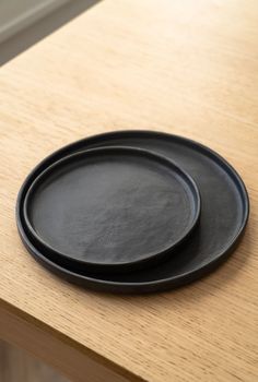 two black plates sitting on top of a wooden table