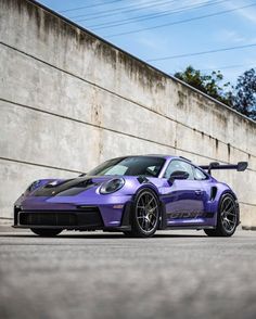 a purple sports car parked in front of a concrete wall