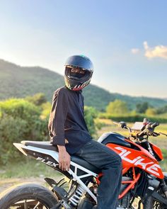 a man sitting on the back of a dirt bike wearing a helmet and blue jeans