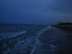 an airplane flying over the ocean on a cloudy night with waves crashing in front of it