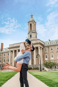 a man and woman kissing in front of a building with a clock tower on it