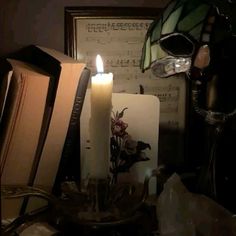 a lit candle sitting on top of a table next to music sheets and a skull