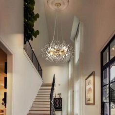 a hallway with stairs and chandelier hanging from the ceiling in front of glass doors