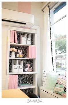 a white shelf filled with lots of pink and white items next to a window sill