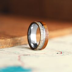 a wooden ring with antler inlays sits on top of a map