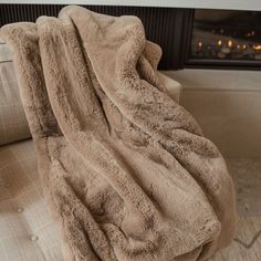 a couch with a blanket on top of it next to a fire place in a living room