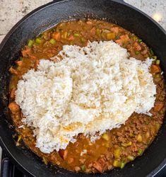 rice is being cooked in a skillet with meat and vegetables on the stove top