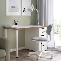 a desk with a chair, lamp and pictures on the wall in front of it