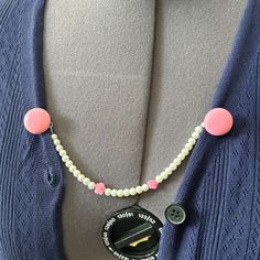 a woman wearing a blue cardigan with pink and white buttons on it's collar