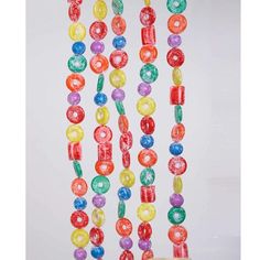 multicolored candy bead necklaces hanging on a white wall in front of a window