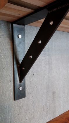 there is a metal hook on the side of a wooden shelf with holes in it