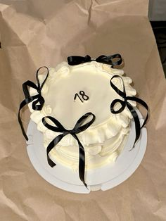 a white cake with black ribbon and monogramming on the top is sitting on a brown paper bag