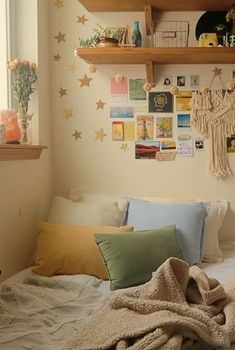 a bed with pillows and blankets on top of it next to a shelf filled with pictures