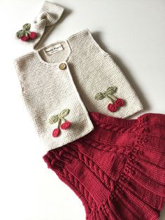 two knitted clothes with cherries on the front and back, one is red