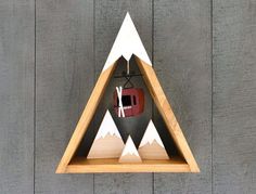 a triangle shaped clock with an apple in the middle and mountains on it's sides