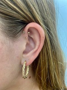 a close up of a woman's ear with two gold hoops on it